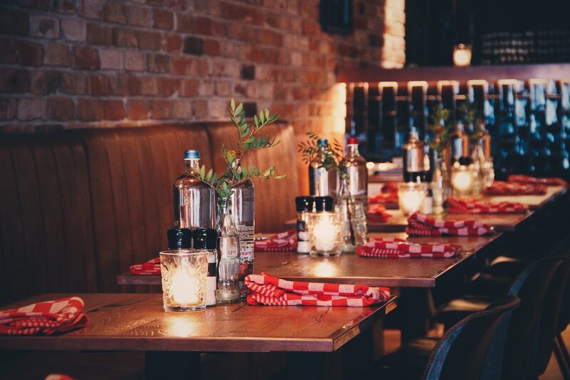 Gedekte tafels met roodgeblokte servetten bij The Chicken Bar